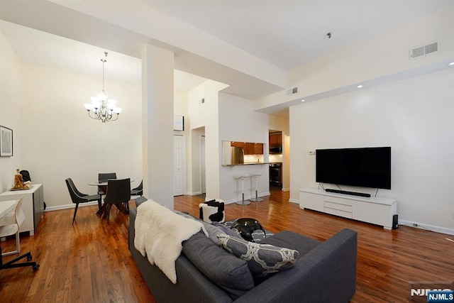 living room with a chandelier, dark wood-type flooring, and baseboards
