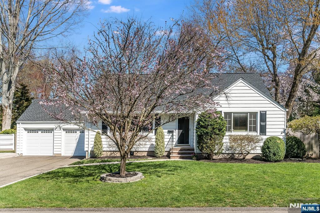 69 Poplar St, Closter, NJ 07624 - view of front of house with concrete driveway, an attached garage, roof with shingles, and a front yard