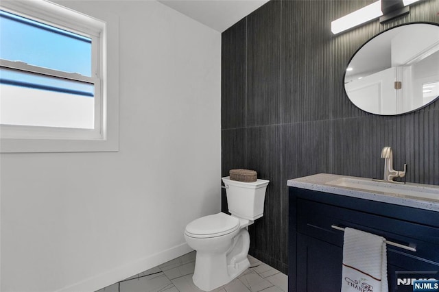 bathroom with marble finish floor, toilet, vanity, and baseboards