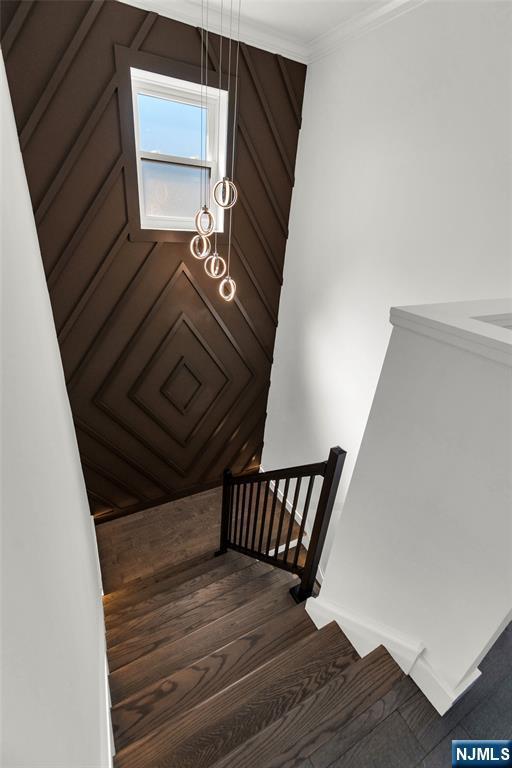 stairway featuring wood finished floors and crown molding