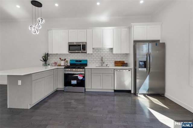 kitchen with stainless steel appliances, a peninsula, a sink, light countertops, and ornamental molding