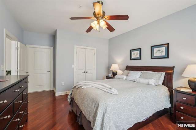 bedroom featuring a ceiling fan, baseboards, dark wood-style floors, and a closet