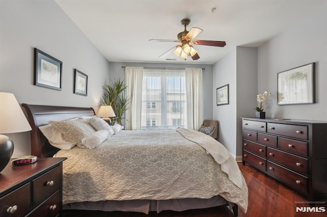 bedroom featuring baseboards, a ceiling fan, and dark wood-style flooring
