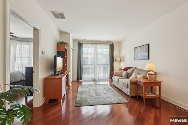 living room featuring visible vents, baseboards, wood finished floors, and a wealth of natural light