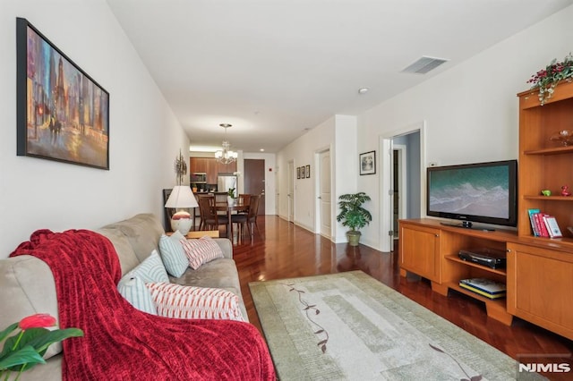 living area featuring visible vents, wood finished floors, and an inviting chandelier