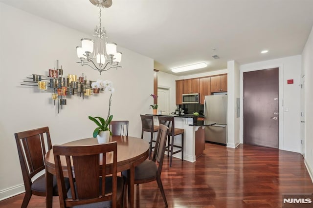 dining area featuring baseboards, a notable chandelier, and dark wood-style floors