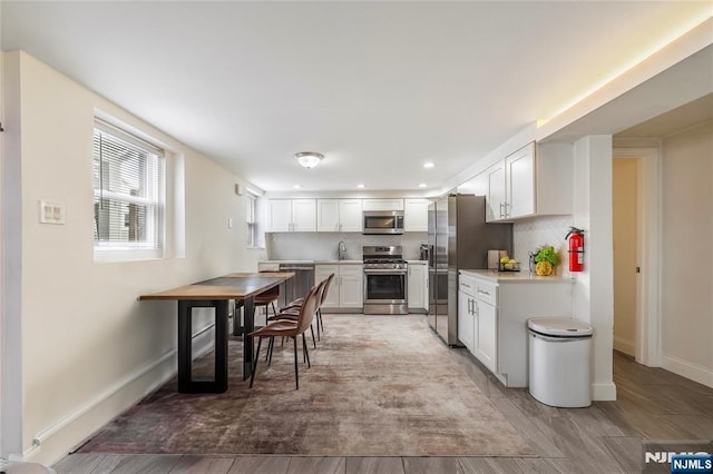 61 Sabina St, Little Ferry, NJ 07643 - kitchen featuring white cabinets, tasteful backsplash, baseboards, light countertops, and appliances with stainless steel finishes