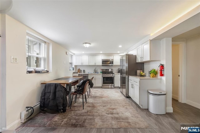 61 Sabina St, Little Ferry, NJ 07643 - kitchen featuring white cabinets, stainless steel appliances, light countertops, backsplash, and baseboards