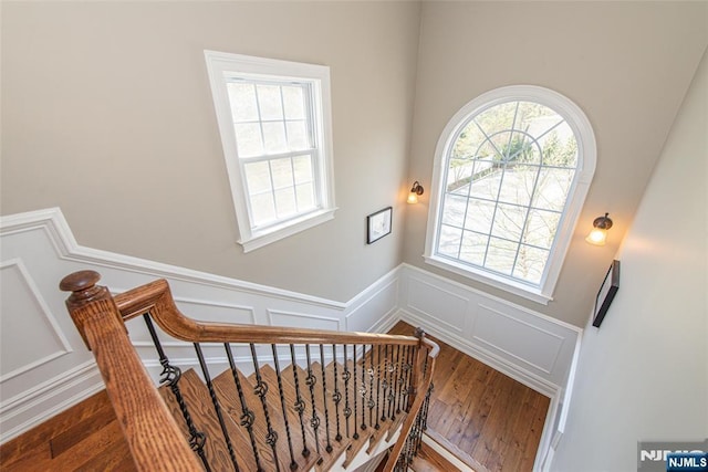 stairs featuring wainscoting, wood finished floors, and a decorative wall