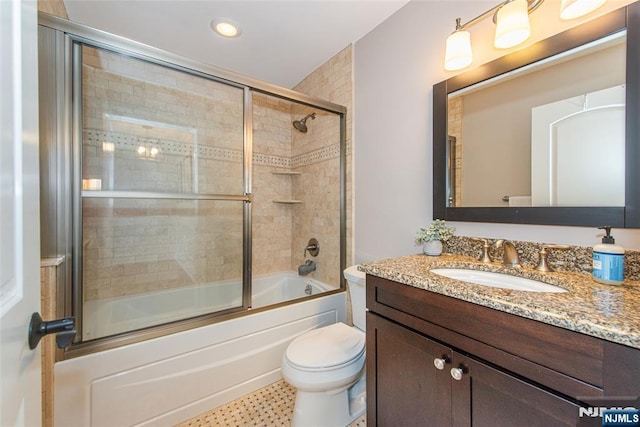 bathroom with vanity, bath / shower combo with glass door, and toilet