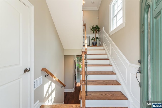 stairway featuring visible vents, crown molding, and wood finished floors