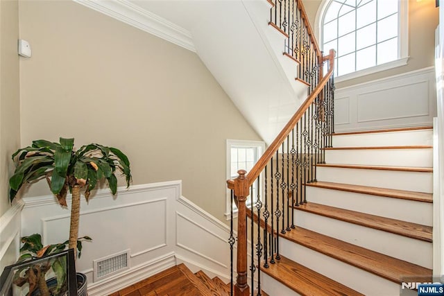 stairway featuring visible vents, a decorative wall, a wealth of natural light, and a wainscoted wall