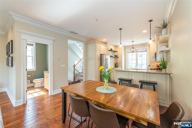 dining space featuring baseboards, light wood-type flooring, stairs, and visible vents