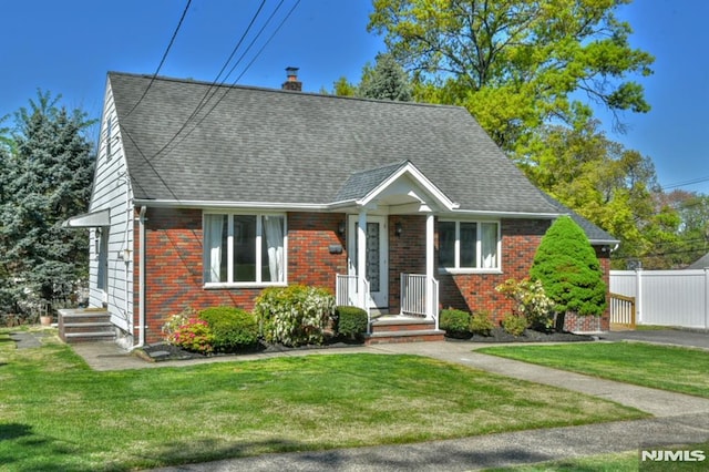 cape cod house featuring brick siding, fence, a chimney, and a front yard
