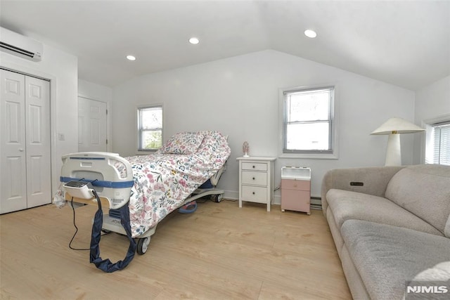 bedroom with multiple windows, light wood-type flooring, and a wall mounted air conditioner