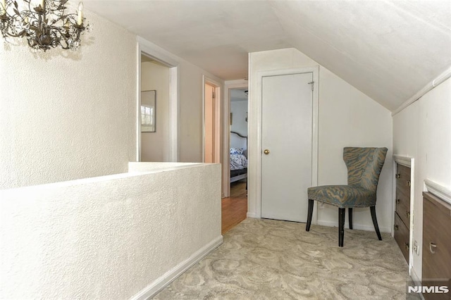 interior space featuring a textured wall, carpet, vaulted ceiling, and a chandelier