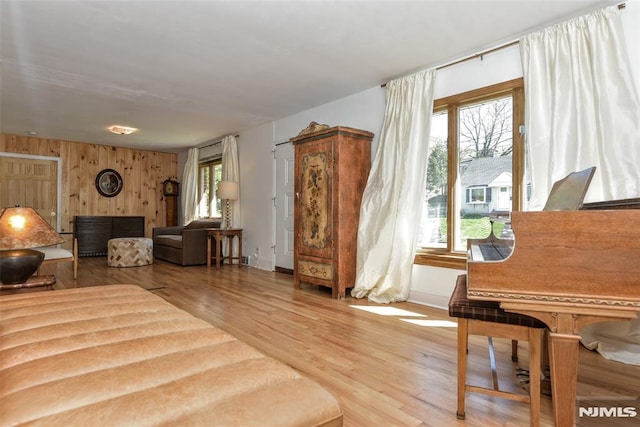 living area with light wood-style floors, wood walls, and baseboards