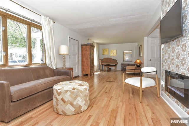 living area with light wood-type flooring, baseboards, and a fireplace
