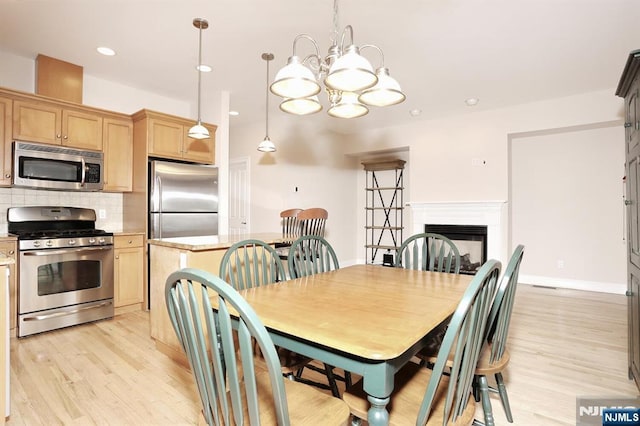 dining space featuring recessed lighting, an inviting chandelier, light wood-type flooring, baseboards, and a fireplace