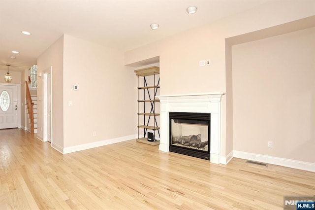 unfurnished living room with recessed lighting, light wood-style flooring, baseboards, and a multi sided fireplace