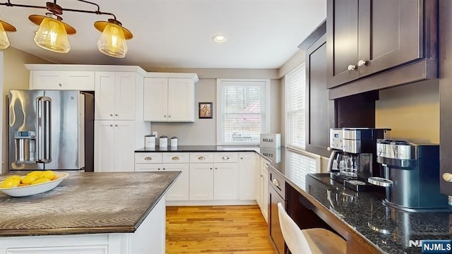 kitchen with white cabinets, dark stone counters, light wood-type flooring, recessed lighting, and stainless steel fridge with ice dispenser