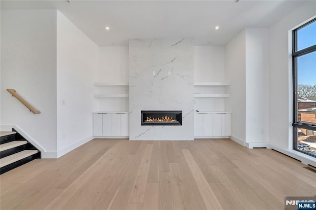 unfurnished living room with baseboards, wood finished floors, a fireplace, and built in shelves