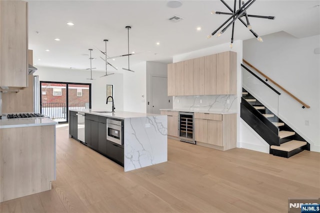 kitchen with wine cooler, a sink, visible vents, modern cabinets, and light brown cabinets