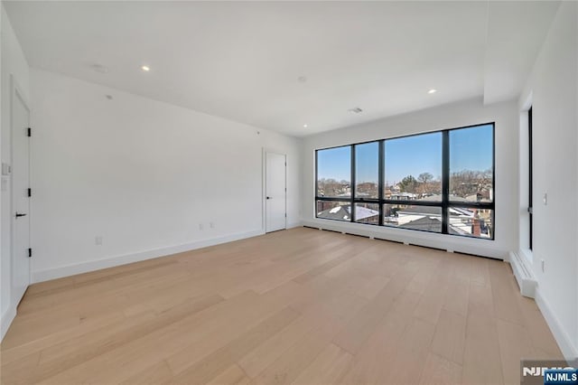empty room featuring recessed lighting, light wood-style flooring, and baseboards