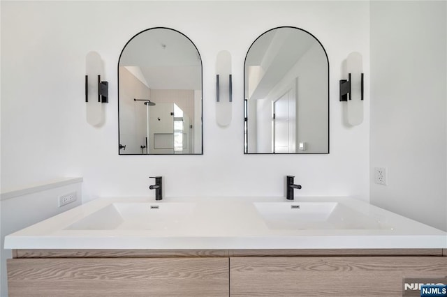 full bathroom with double vanity, a shower, and a sink