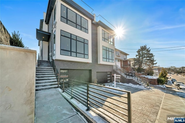 view of front of property with an attached garage, stairs, and stucco siding