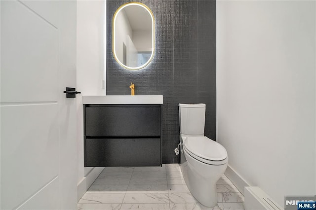 bathroom with toilet, baseboards, marble finish floor, vanity, and a baseboard radiator