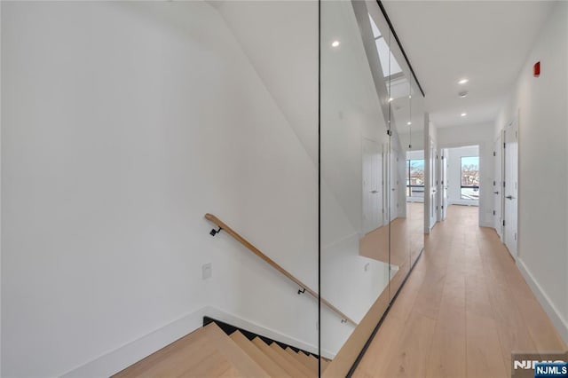 hallway with recessed lighting, light wood-style floors, baseboards, and an upstairs landing