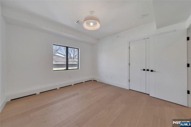 unfurnished bedroom featuring a closet, visible vents, and light wood finished floors