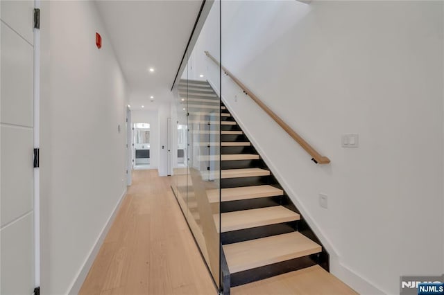 stairway with baseboards, wood finished floors, and recessed lighting