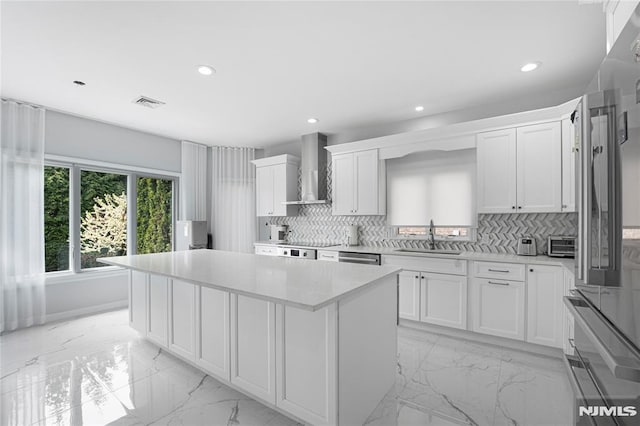 kitchen featuring a kitchen island, a sink, marble finish floor, recessed lighting, and wall chimney exhaust hood