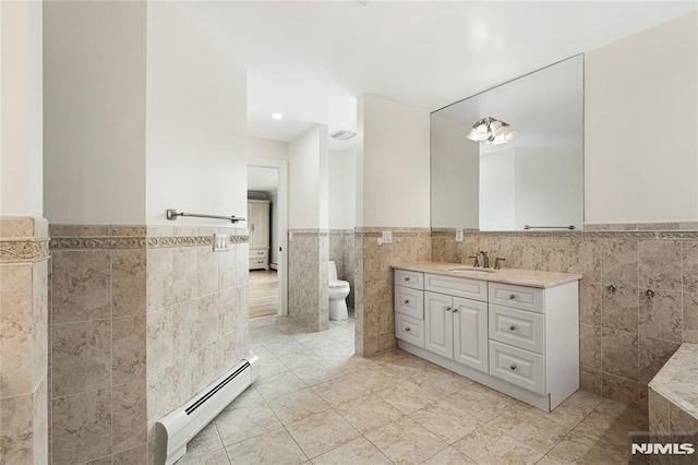 bathroom with tile walls, wainscoting, tile patterned flooring, and a baseboard radiator