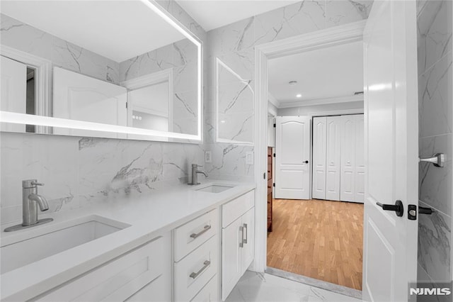 full bath featuring double vanity, decorative backsplash, a sink, and marble finish floor