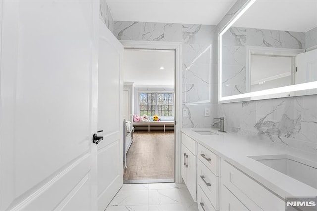 full bath with double vanity, a sink, marble finish floor, and ensuite bath