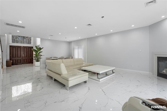 living room featuring visible vents, marble finish floor, and a glass covered fireplace