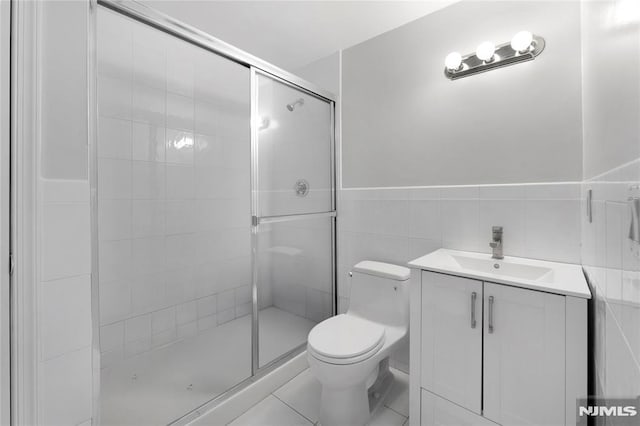 full bath featuring vanity, a stall shower, toilet, and tile walls