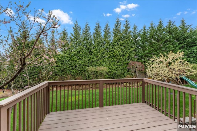 wooden deck with a lawn and a playground