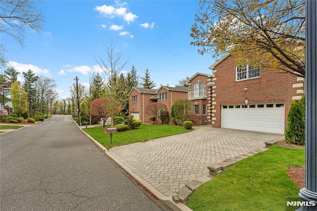 traditional-style home with a residential view, an attached garage, decorative driveway, and a front yard