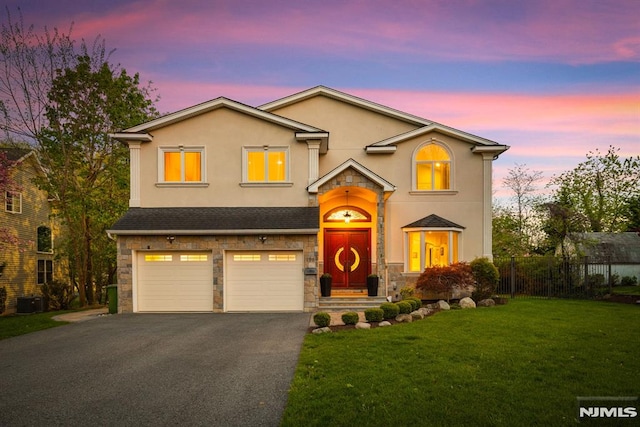 traditional home with fence, an attached garage, a front lawn, aphalt driveway, and stone siding