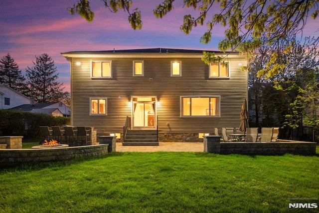 back of property at dusk featuring a patio, a fire pit, and a yard