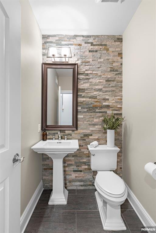 half bathroom with toilet, baseboards, visible vents, and wood finished floors