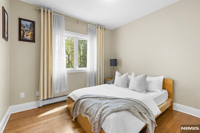 bedroom featuring baseboards, wood finished floors, and baseboard heating
