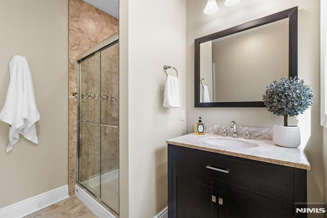 bathroom with baseboards, vanity, and a shower stall
