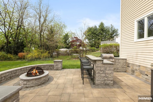 view of patio / terrace with a fire pit, exterior kitchen, outdoor dry bar, and a grill
