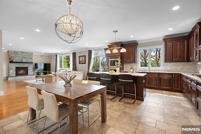 dining area with crown molding, a fireplace, recessed lighting, and a chandelier