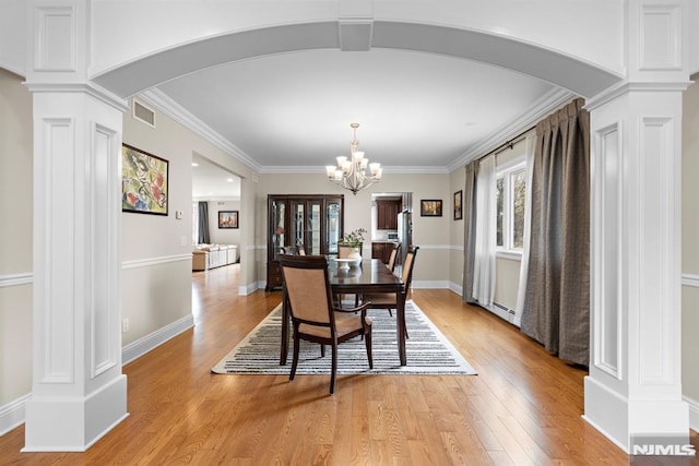 dining area with decorative columns, light wood finished floors, visible vents, and a baseboard radiator